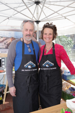 David Clark und Julia Schlutius mit Schürzen am Marktstand von Alaska Wildfisch 