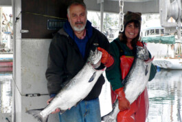 David Clark und Julia Schlutius jeweils mit einem frisch gefangenen Lachs in der Hand